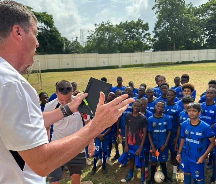 Young Nigerian footballers train under coaches in development academies.